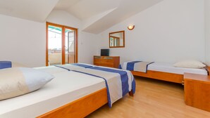 Une chambre avec deux lits, une commode en bois et un miroir au mur.