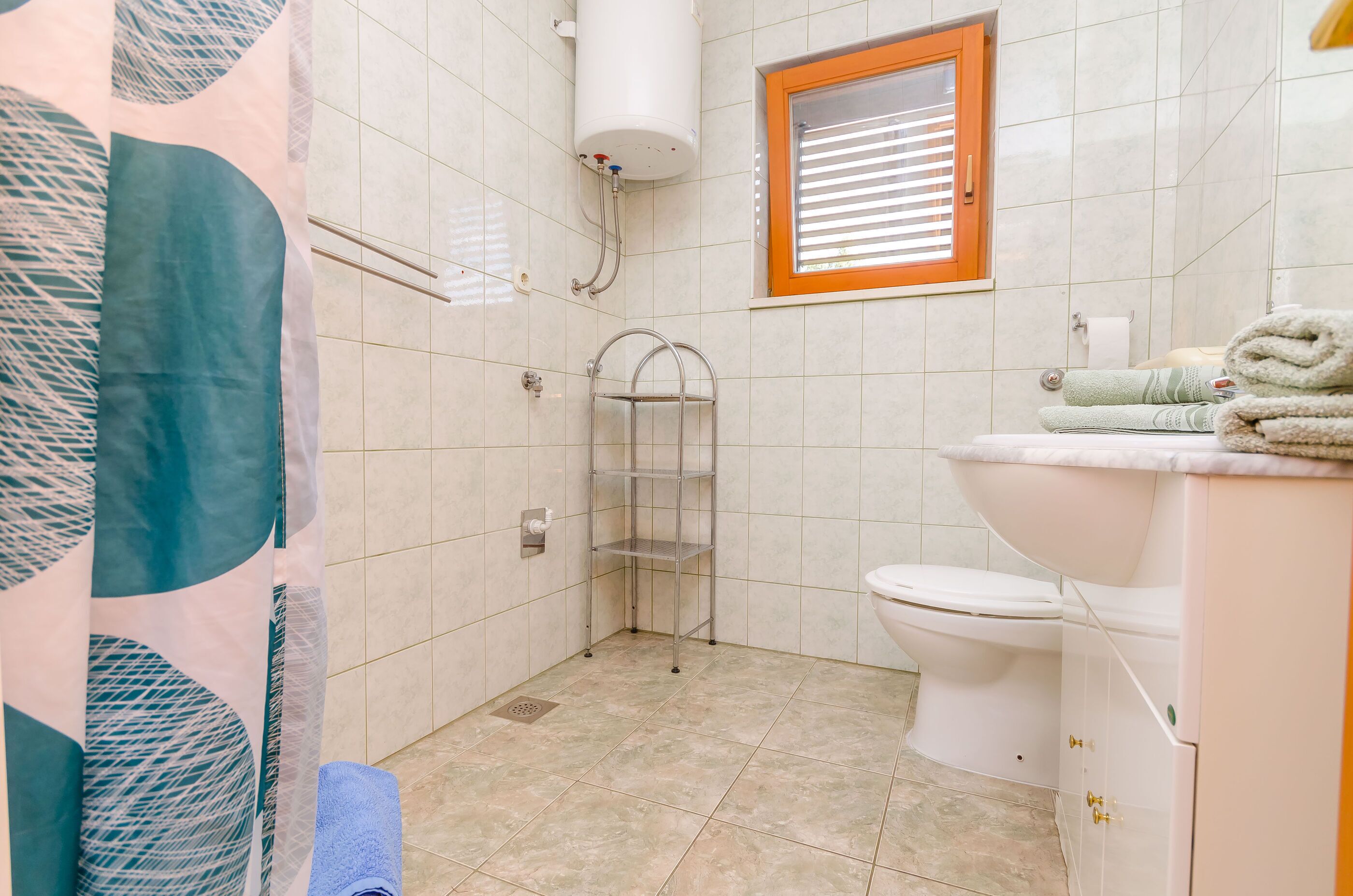 A bathroom with a toilet, sink, shower, and a towel rack.