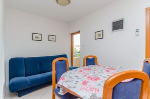 A room with a blue sofa, a floral tablecloth-covered table, and two chairs. - Apartments Milivoj (Seget)