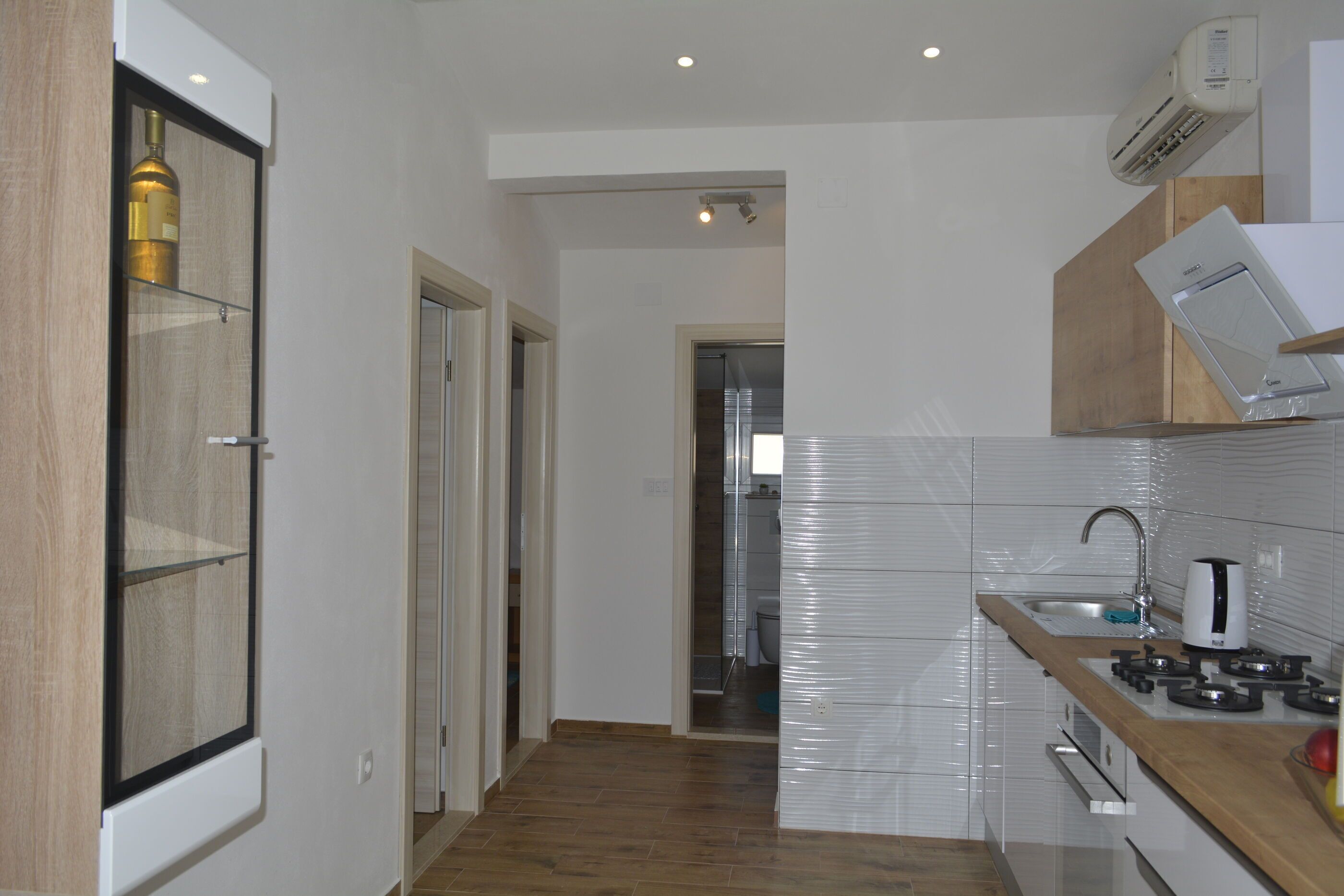 A modern kitchen with a wooden countertop, white cabinets, and a stainless steel sink.
