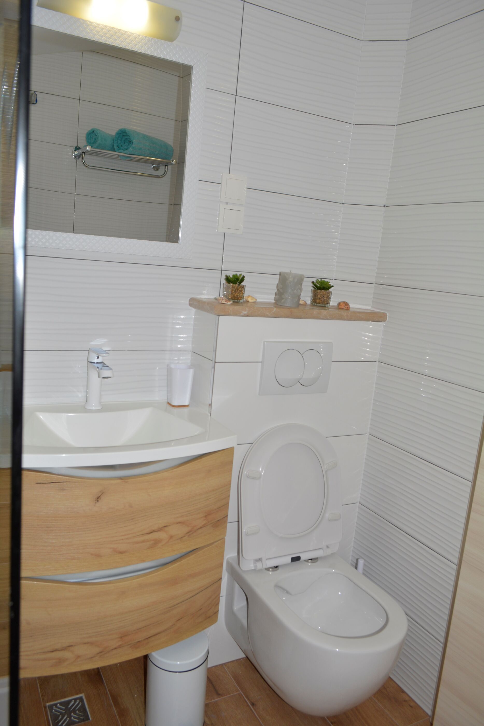 A modern bathroom with a white sink, wooden vanity, and a toilet.