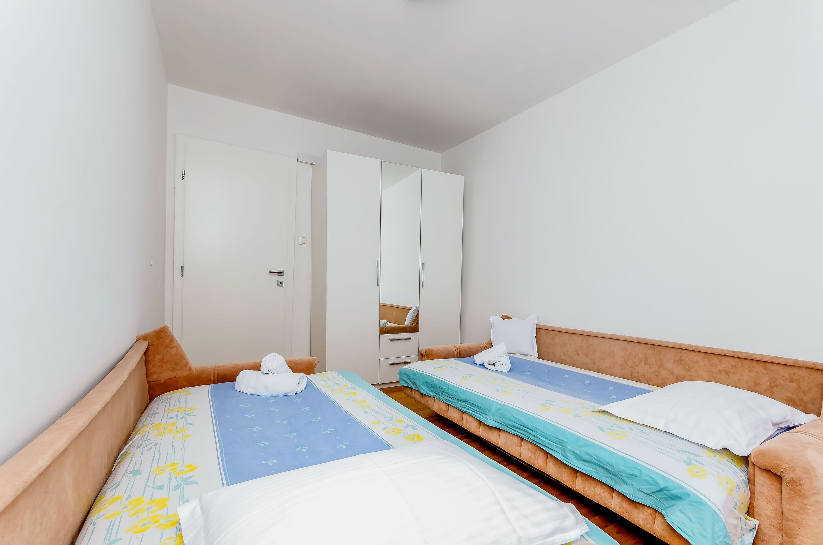 Habitación de hotel con dos camas individuales, un armario y un espejo.