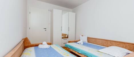 Habitación de hotel con dos camas individuales, un armario y un espejo.
