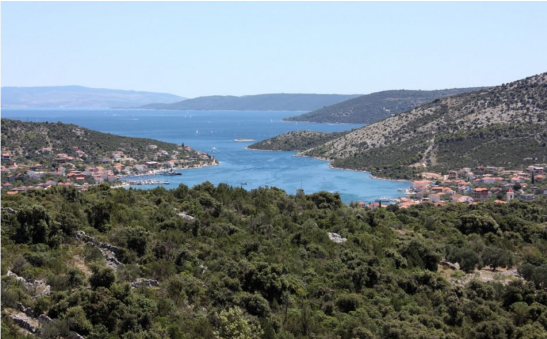 Un pueblo costero con abundante vegetación y un mar azul cristalino.