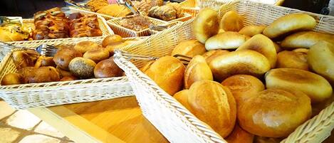 A buffet table with various breads and pastries.