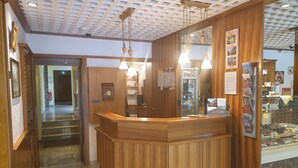 Un espace d’accueil avec un comptoir en bois, un réfrigérateur à boissons de la marque Coca-Cola et un panneau d’affichage où sont accrochées des cartes postales.