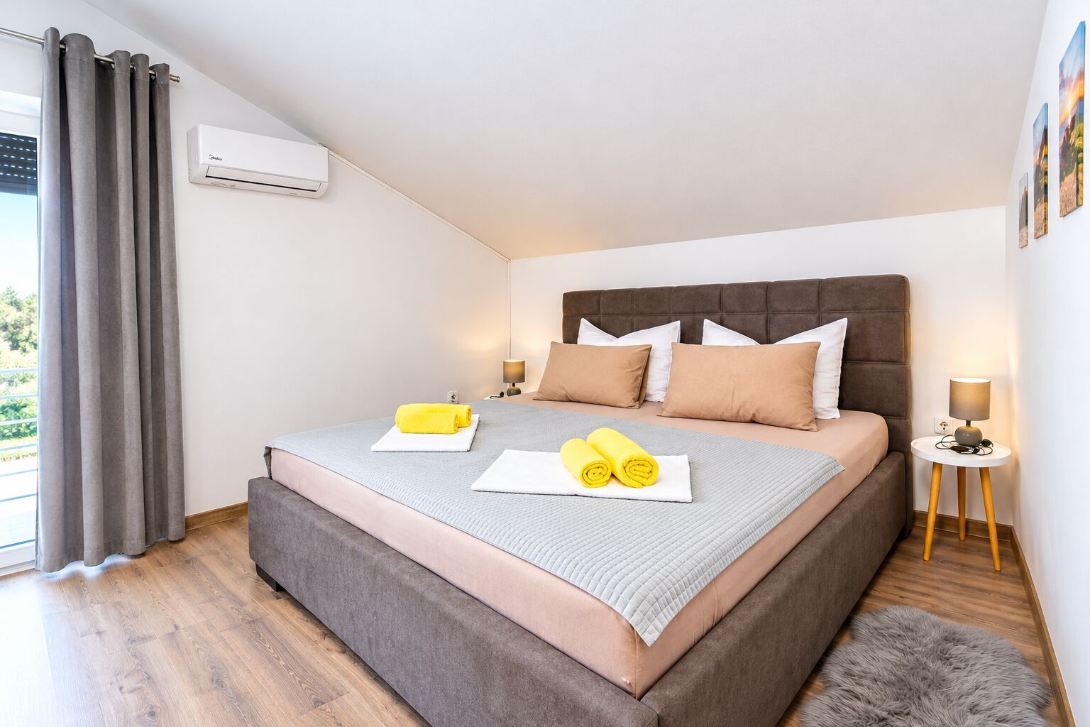 A modern bedroom with a large bed, a headboard, a bedside table with a lamp, and a window with curtains.