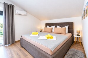 Ein modernes Schlafzimmer mit einem großen Bett, einem Kopfteil, einem Nachttisch mit Lampe und einem fenster mit Vorhängen.