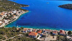 A coastal village with houses along the shoreline, a clear blue sea, and a small island in the distance. - Apartments Val (Vinisce)