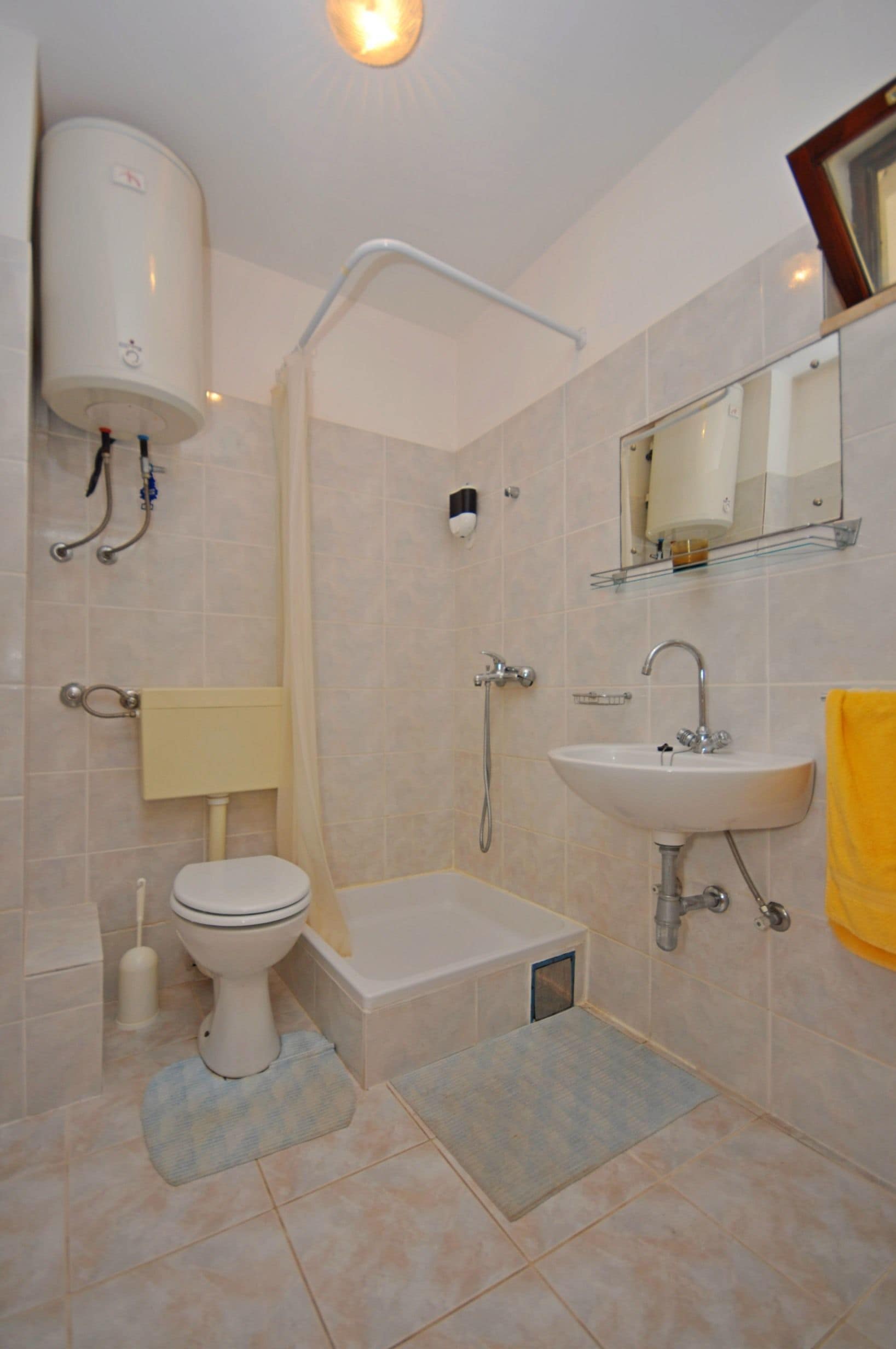 A bathroom with a toilet, sink, shower, and a mirror.