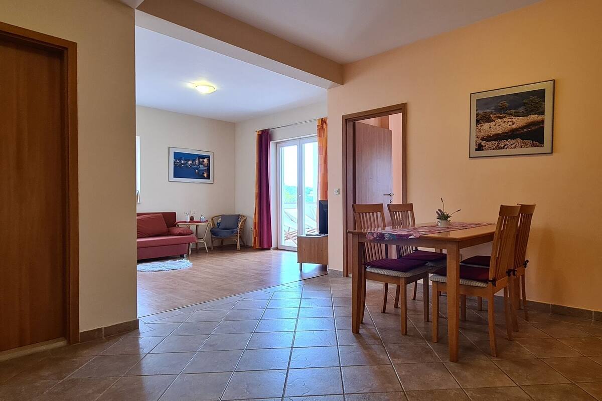 Amplia sala de estar con un sofá rojo, una mesa de comedor con sillas y una zona de cocina con estufa.