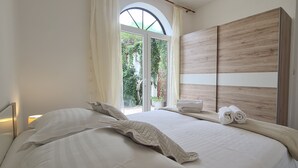 A bedroom with a large bed, a wooden wardrobe, and a door. - Apartment Nikola (Jelsa)