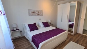 Une chambre à coucher comprenant un lit, des tables de chevet, une armoire et un miroir.