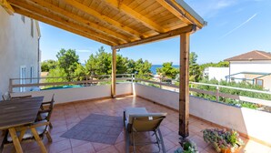 Une terrasse couverte avec un plafond en bois, une table, des chaises et une vue sur la mer.