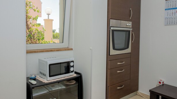 Cozinha com micro-ondas, forno e janela com vista para área verde.