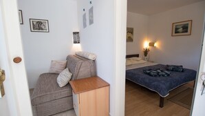 Ein Schlafzimmer mit einem Bett, einer Couch und einem kleinen Holztisch. An den Wänden sind Wandleuchten und gerahmte Bilder angebracht.