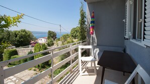 Ein Balkon mit Tisch und Stühlen, der einen schönen Blick auf das Meer und die umliegende Vegetation bietet.