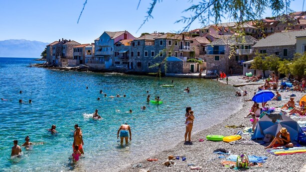 A coastal town with stone buildings, clear blue waters, and people swimming and relaxing on the beach. - Apartments Kaja (Postira)