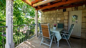 A covered outdoor seating area with stone walls, a table, and chairs. - Apartments Kaja (Postira)