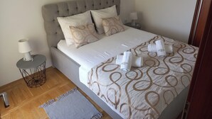 A neatly made bed with a patterned bedspread, two pillows, and rolled towels on the side. - Apartments Bogdan (Pisak)