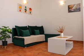 A living room with a green sofa, a white coffee table, and a potted plant.