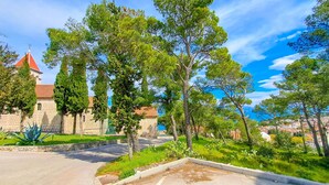 Un parcheggio con un edificio in pietra e alberi sullo sfondo.