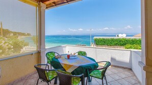 Un balcone con tavolo e sedie, vista sulla costa.