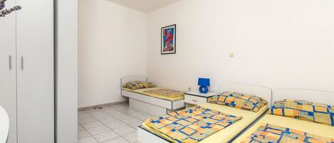 Ein Schlafzimmer mit zwei Betten, einem kleinen Nachttisch, einem Schrank und einem gerahmten Bild an der Wand.