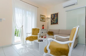 Ein Wohnzimmer mit einer Couch, zwei Sesseln, einem Couchtisch und einem Gemälde an der Wand.