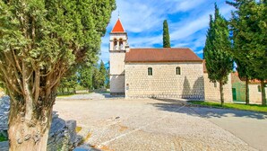 A stone building with a red-tiled roof and a bell tower. - Apartments Jerko (Sutivan)