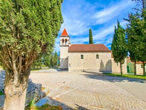 A stone building with a red-tiled roof and a bell tower. - Apartments Jerko (Sutivan)