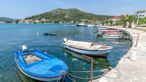 Una marina con diverse imbarcazioni ormeggiate, acqua limpida e montagne sullo sfondo.