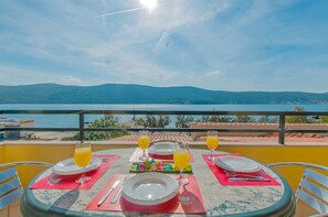 A table set for breakfast with a view of the sea and mountains.