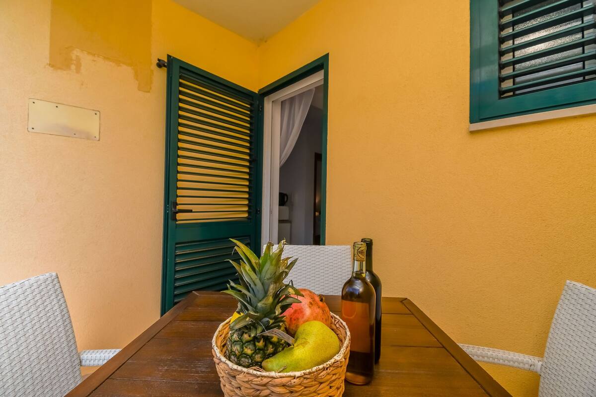 A dining table with a fruit basket, a bottle, and a chair.