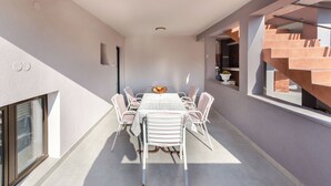 A modern dining area with a long table, white chairs, and a central vase. - Apartment Albina (Palit)
