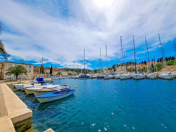 A marina with boats docked, a stone building, and a clear sky.