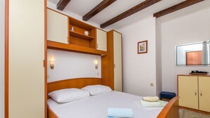 Une chambre à coucher comprenant un lit, une armoire en bois, des lampes de chevet et une petite étagère ornée d’objets décoratifs.