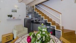 Una cocina moderna con una escalera de madera, una mesa de comedor con flores y un sofá.