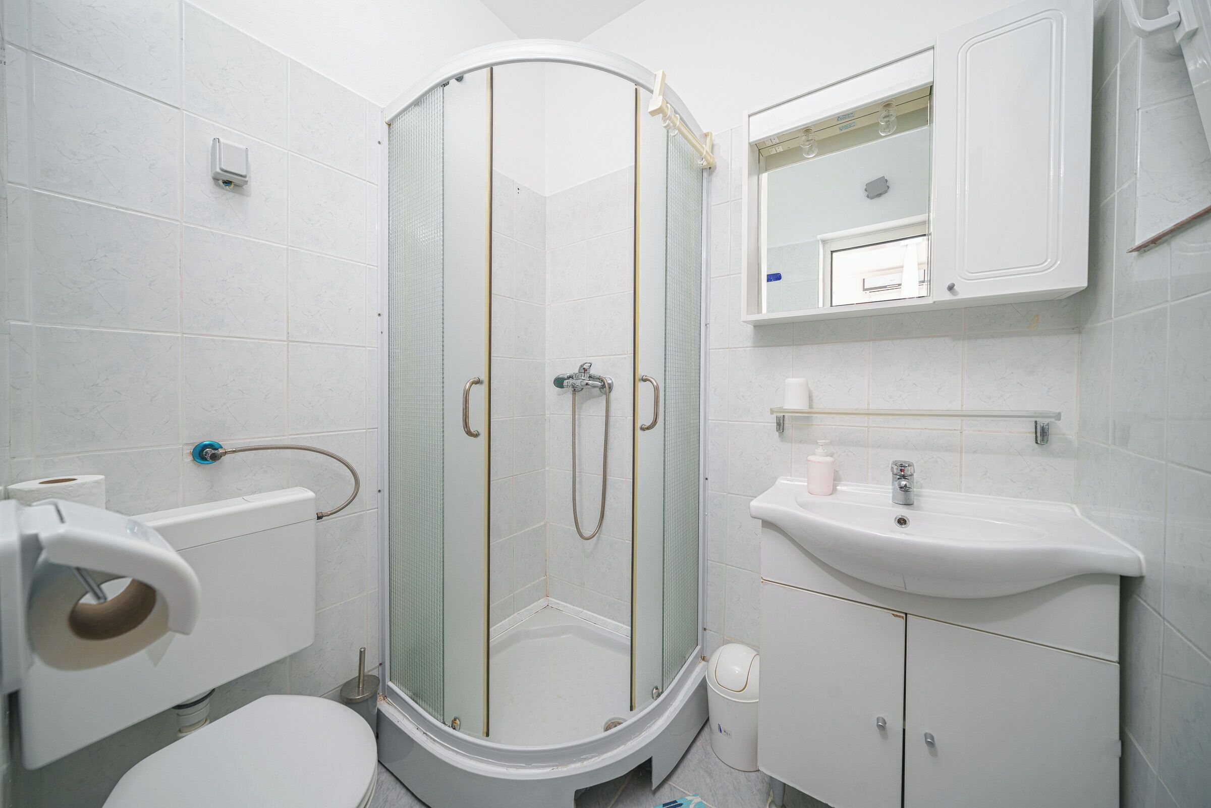 Un bagno con il water, un lavandino, un box doccia e uno specchio.
