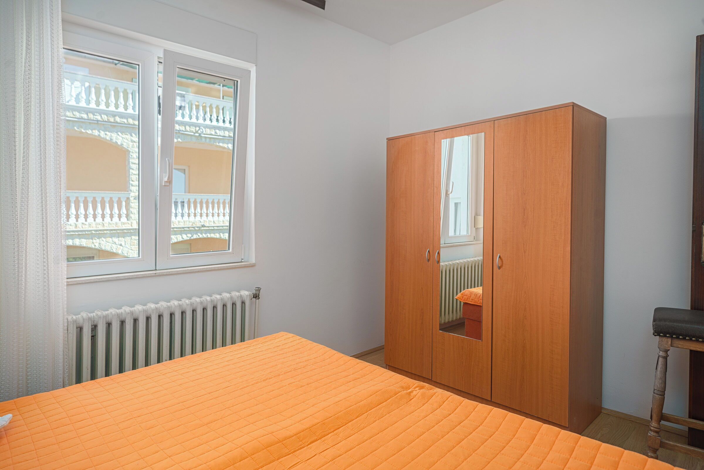 A bedroom with a bed, a wardrobe, a window, and a radiator.