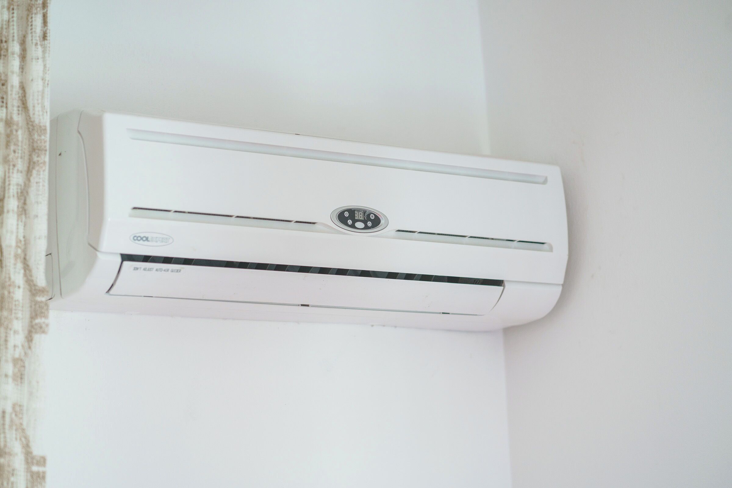 Un equipo de aire acondicionado blanco instalado en la pared, con un panel de control y una etiqueta.