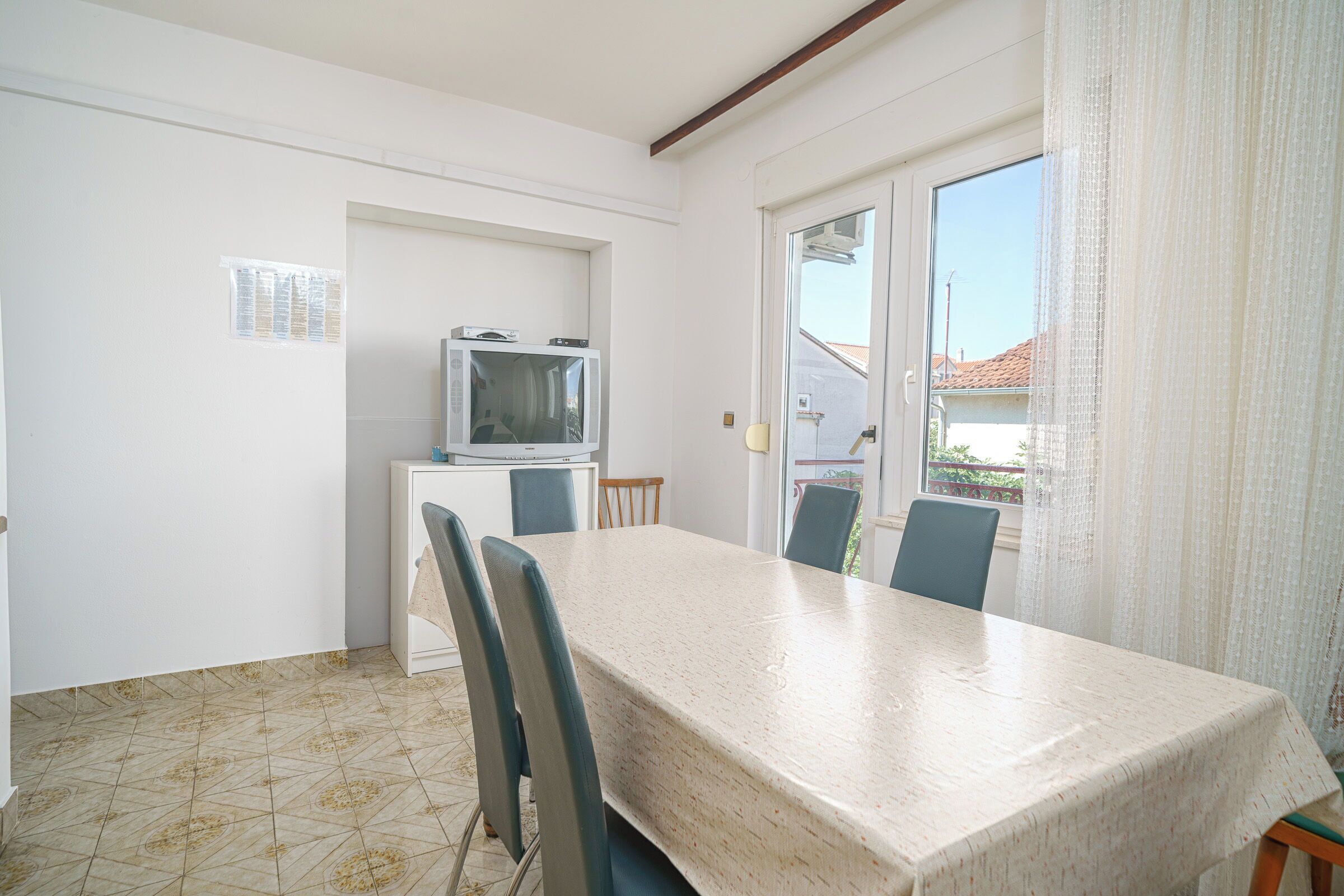 A dining area with a table and chairs, a small kitchenette with a microwave, and a view through a glass door.