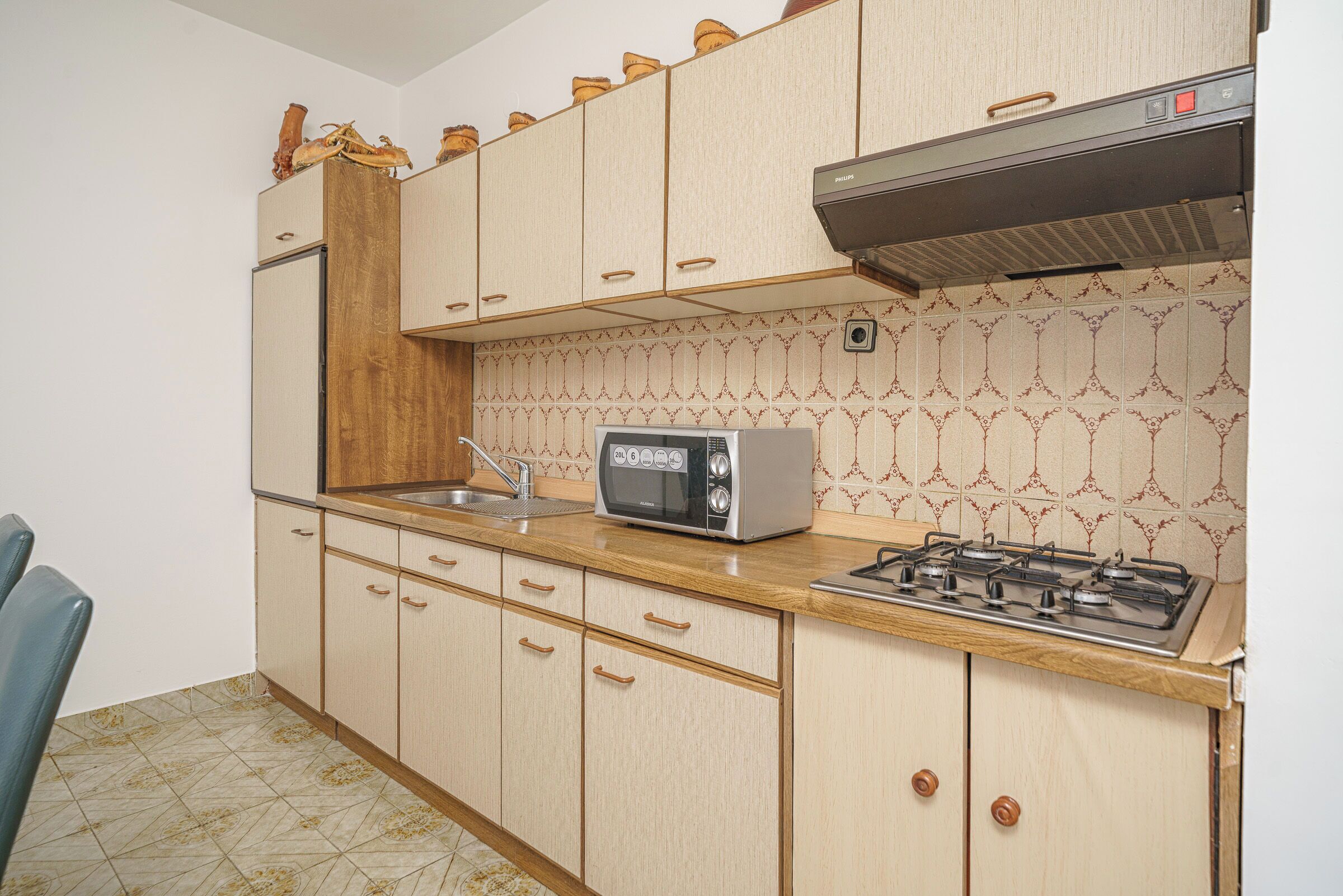 A kitchen with wooden cabinets, a microwave, a gas stove, and a sink.