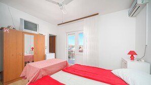 Ein Schlafzimmer mit zwei Betten, einem Kleiderschrank, einem Fernseher und einem Fenster mit Vorhängen.