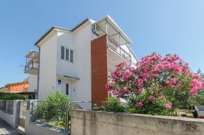 A two-story building with a white facade, a brick section, and a balcony.