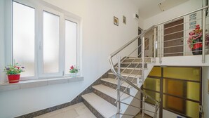 Eine Treppe mit Metallgeländer, ein Fenster mit Milchglas und ein Blumentopf auf dem Fensterbrett.