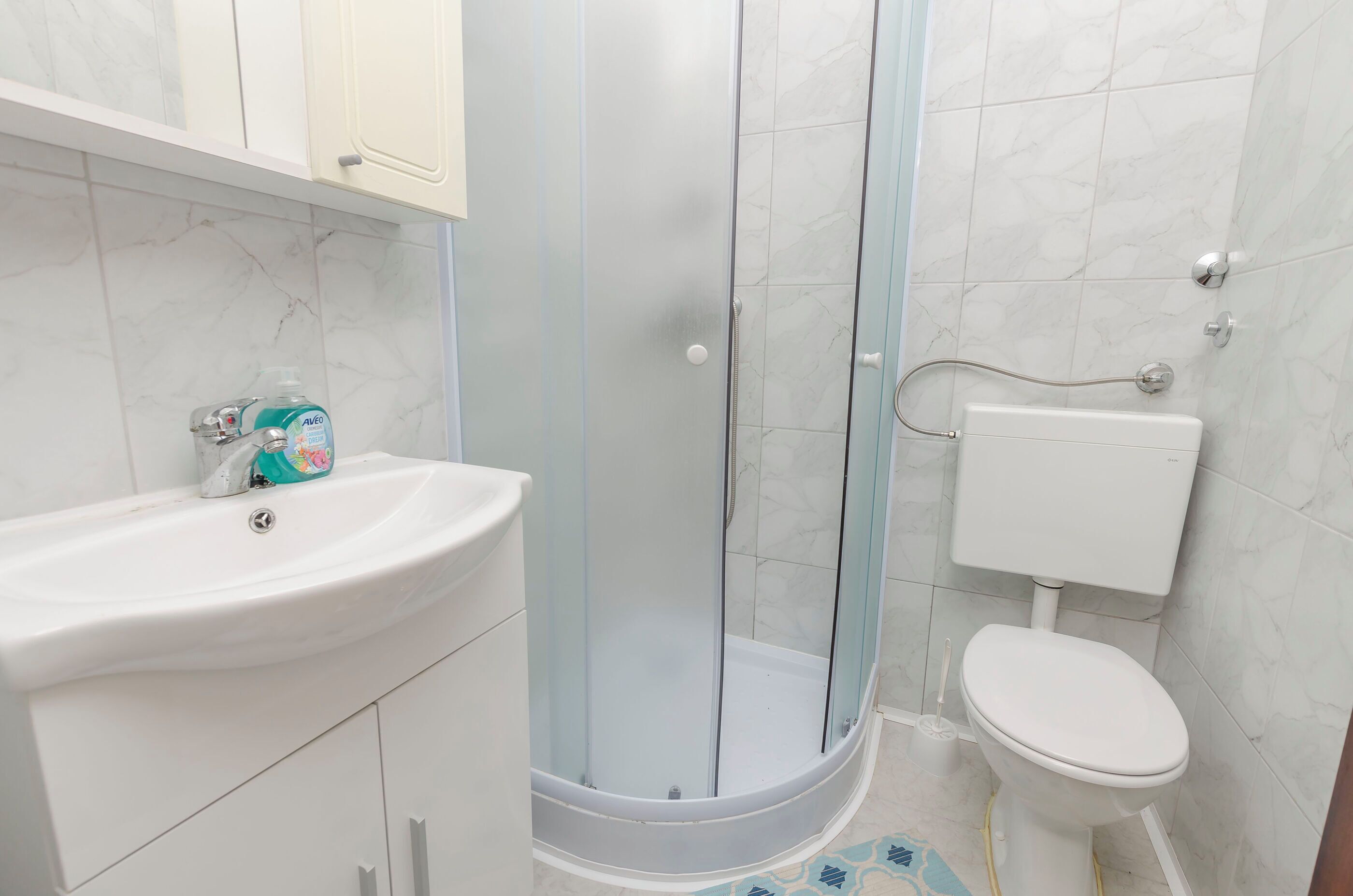Une salle de bain avec une douche à parois de verre, un lavabo blanc et des toilettes.