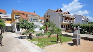 A residential area with houses, a paved walkway, and a stone structure. - Apartment Ines (Vodice)
