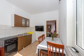A compact kitchen with wooden cabinets, a built-in oven, and a dining area with a table and chairs.