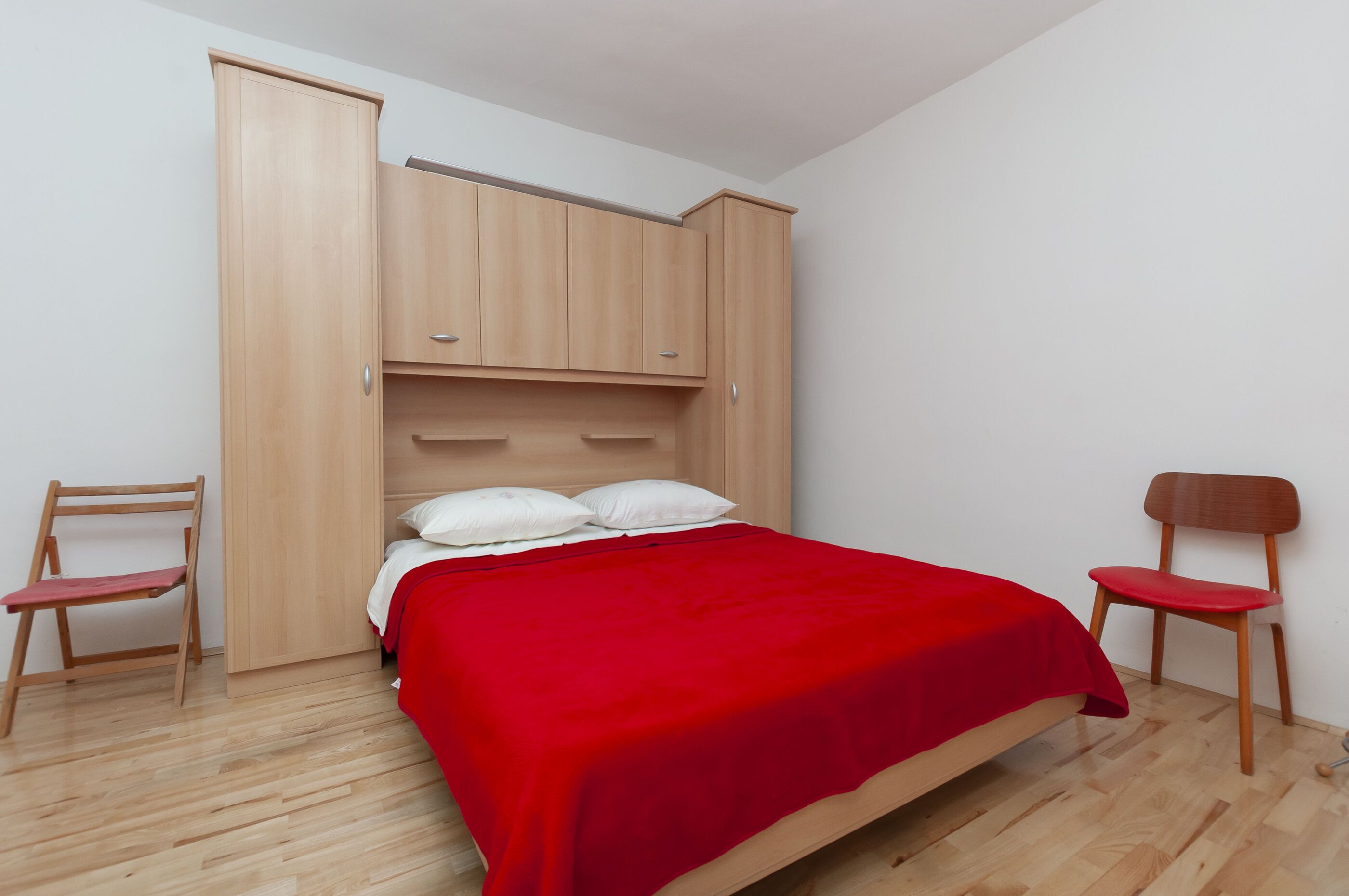 Una camera da letto con un letto, un armadio in legno e due sedie di legno.